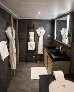 La salle de bains est pourvue de serviettes blanches accrochées au mur. dans l'établissement Le K2 Djola, à Courchevel