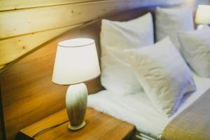 una lámpara en una mesa junto a una cama con almohadas en Svetliy Terem Hotel en Suzdal