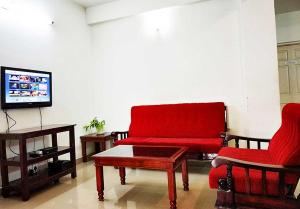 a living room with a red couch and a coffee table at Honey Bee Serviced Apartments Trivandrum in Trivandrum