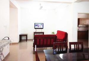 Una sala de estar con un sofá rojo y una mesa. en Honey Bee Serviced Apartments Trivandrum, en Trivandrum 5 fotos más