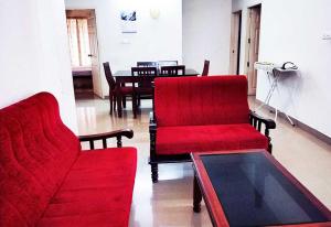 Una sala de estar con dos sillas rojas y una mesa. en Honey Bee Serviced Apartments Trivandrum, en Trivandrum
