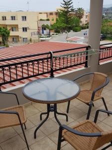 einen Glastisch und zwei Stühle auf dem Balkon in der Unterkunft Mikes Apartment in Georgioupoli