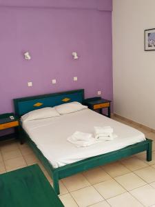 ゲオルギオポリスにあるMikes Apartmentの紫の壁のベッドルーム1室(ベッド1台、テーブル2台付)
