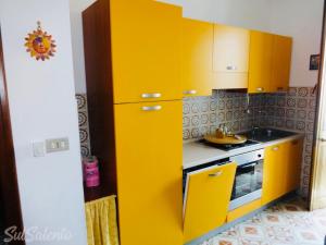 トッレ・サン・ジョヴァンニ・ウジェントにあるAppartamento Giamaicaのキッチン(黄色のキャビネット、コンロ付)