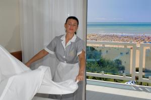 una donna in piedi accanto a un letto in una stanza d'albergo di Majestic Beach Hotel & Wellness a Bibione