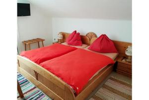 um quarto com uma cama de madeira e lençóis vermelhos em Pension Charlotte em Bad Gastein