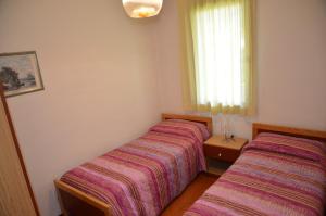 twee bedden in een kleine kamer met een raam bij Ville Carla e Caterina in Bibione +12 foto's