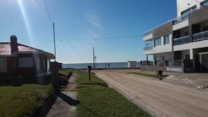 eine unbefestigte Straße neben einem Gebäude mit dem Ozean in der Unterkunft Villa Bono in Santa Clara del Mar