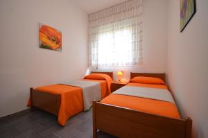 two beds in a small room with a window at Appartamenti Villa Angela in Bibione