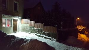 a house is covered in snow at night at Apartament Grosik in Duszniki Zdrój