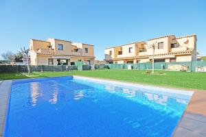 a blue swimming pool in front of a building at Holiday Home Rosa in L'Escala