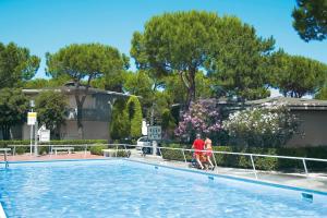 dos personas caminando alrededor de una piscina en Villaggio San Siro, en Bibione