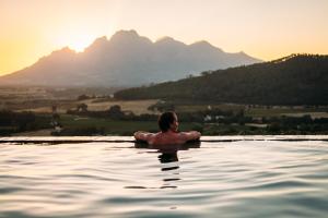 un uomo in una piscina con montagne sullo sfondo di 7 Koppies a Franschhoek