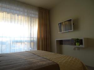 een slaapkamer met een bed en een raam met een televisie bij Апартамент 13 in Hisarya