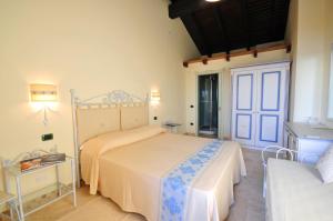 a bedroom with a bed and a table and a door at Hotel Corsaro Nero in Portu Maga