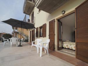 a patio with white chairs and an umbrella at Appartamenti Le Terme in Rapolano Terme