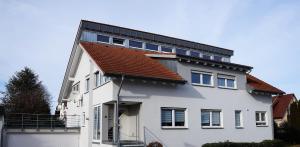 una casa bianca con tetto rosso di BodenSEE Apartment "La Musica" a Meckenbeuren