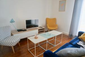 a living room with a tv and a couch and chairs at Le 27 - Cosy appartement centre-ville - WIFI in Royan