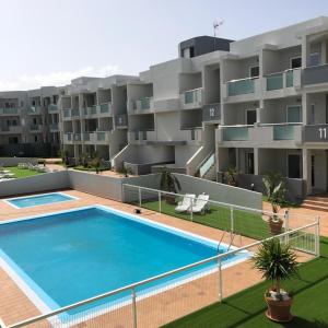ein Apartment mit einem Pool vor einem Gebäude in der Unterkunft Luxury Apartment in Corralejo