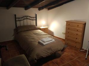 ein Schlafzimmer mit einem Bett mit einer Kommode und einer Lampe in der Unterkunft Casa Rural Vega del Tajuña in Armuña de Tajuña