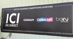 a sign on a wall with different brands on it at Kyriad Direct Saintes in Saintes