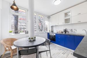 cocina con armarios azules, mesa y sillas en Ada Bucharest Apartment en Bucarest