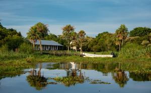 a house with a boat in the middle of a lake at Posada de la Laguna in Colonia Carlos Pellegrini