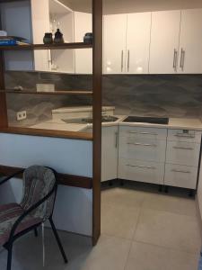 a kitchen with white cabinets and a chair and a table at Apartment NECA in Lovište
