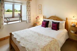 a bedroom with a large bed with purple pillows at Arbor Holiday Cottages in Southam