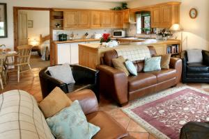 a living room with leather furniture and a kitchen at Arbor Holiday Cottages in Southam +20 photos