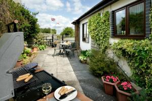 a small patio with a table and a grill at Arbor Holiday Cottages in Southam