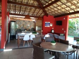 ein Restaurant mit Tischen, Stühlen und roten Wänden in der Unterkunft Itacimirim - Quinta das Lagoas Residence in Itacimirim