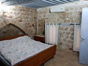 a bedroom with a bed and a stone wall at Nzar Khoury for Hosting in Acre