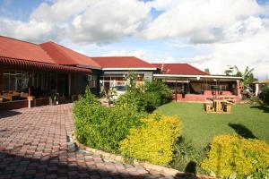 a building with a brick walkway in front of a yard at Honeybed Lodge in Lusaka