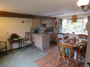 cocina y comedor con mesa y sillas en The Byre, en Llandovery