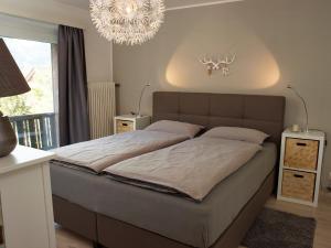 a bedroom with a large bed and a chandelier at Karwendel Apartments II in Scharnitz