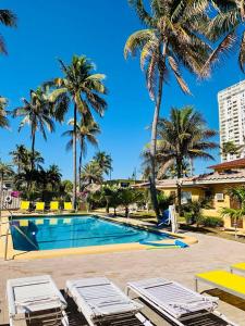 uma piscina com duas espreguiçadeiras e palmeiras em Ebb Tide Resort em Pompano Beach