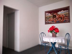 a table with chairs and a vase with red flowers on it at Campo Grande Pousar ou morar in Rio de Janeiro