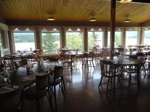 a dining room with tables and chairs and windows at Duck Cove Inn in Margaree Harbour