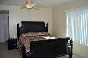 a black bed in a bedroom with a ceiling fan at Rosarito Inn in Rosarito