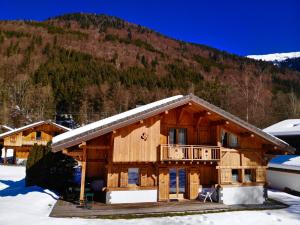 une cabane en rondins dans la neige avec une montagne dans l'établissement Chalet Pétérets, à Samoëns