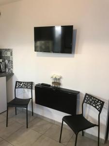 two chairs and a desk with a television on a wall at LE MONICA in Narbonne