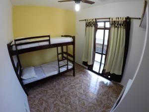 Praia Linda Hospedagem في أرايال دو كابو: غرفة بسريرين بطابقين ونافذة