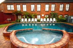 a swimming pool with chairs and a building at Buckingham Apartments in Highett
