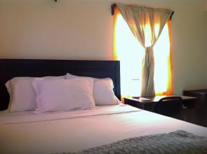 Schlafzimmer mit einem weißen Bett und einem Fenster in der Unterkunft Beacon Rise Apartment in Basseterre