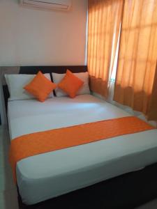 a bed with orange and white pillows in a room at Hotel Torres del Parque No3 in Barranquilla