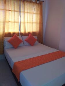 uma cama com almofadas laranja e branca num quarto em Hotel Torres del Parque No3 em Barranquilla