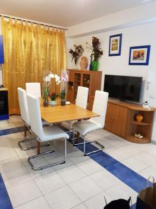 Un comedor con una mesa de madera y sillas blancas. en Taormina Mare Piscina Fondachello, en Fondachello