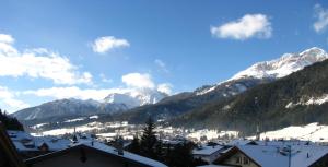 a town with snow covered mountains in the background at Hotel Nès Crépes in Pozza di Fassa