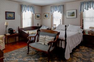 a bedroom with a bed and a chair and windows at Clary Lake Bed and Breakfast in Jefferson